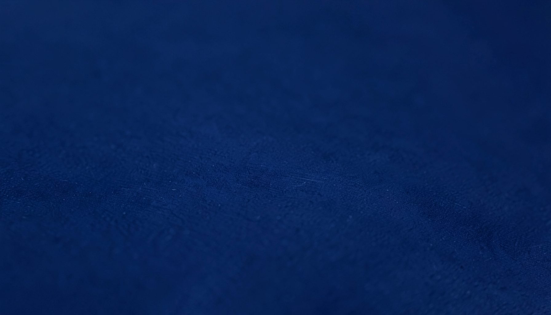 A close-up photograph of a smooth matte surface in deep navy blue, with subtle texture resembling brushed metal, conveying a calm and professional mood.